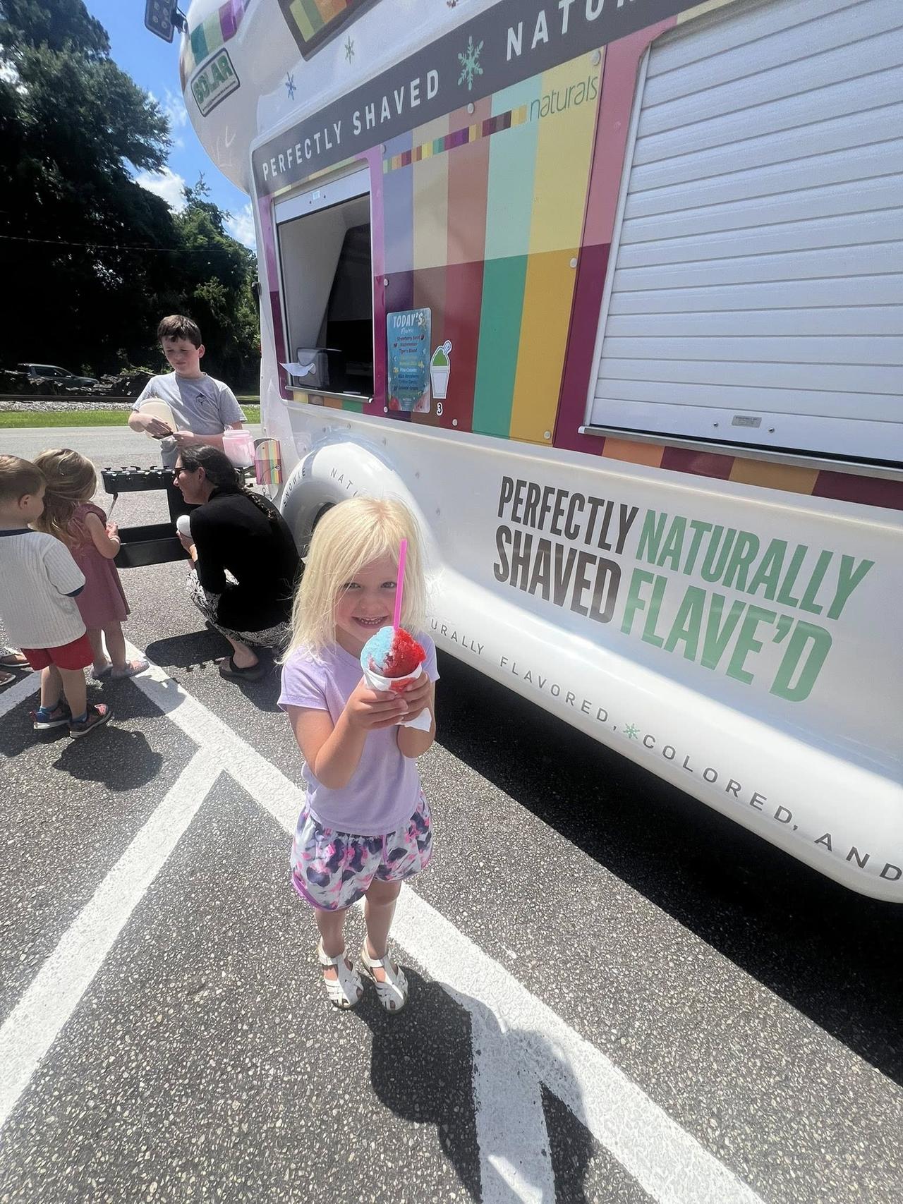 School kids and families enjoying shaved ice at outdoor event